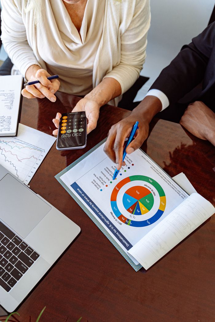 hero Two business professionals discussing financial documents and strategies at an office desk.