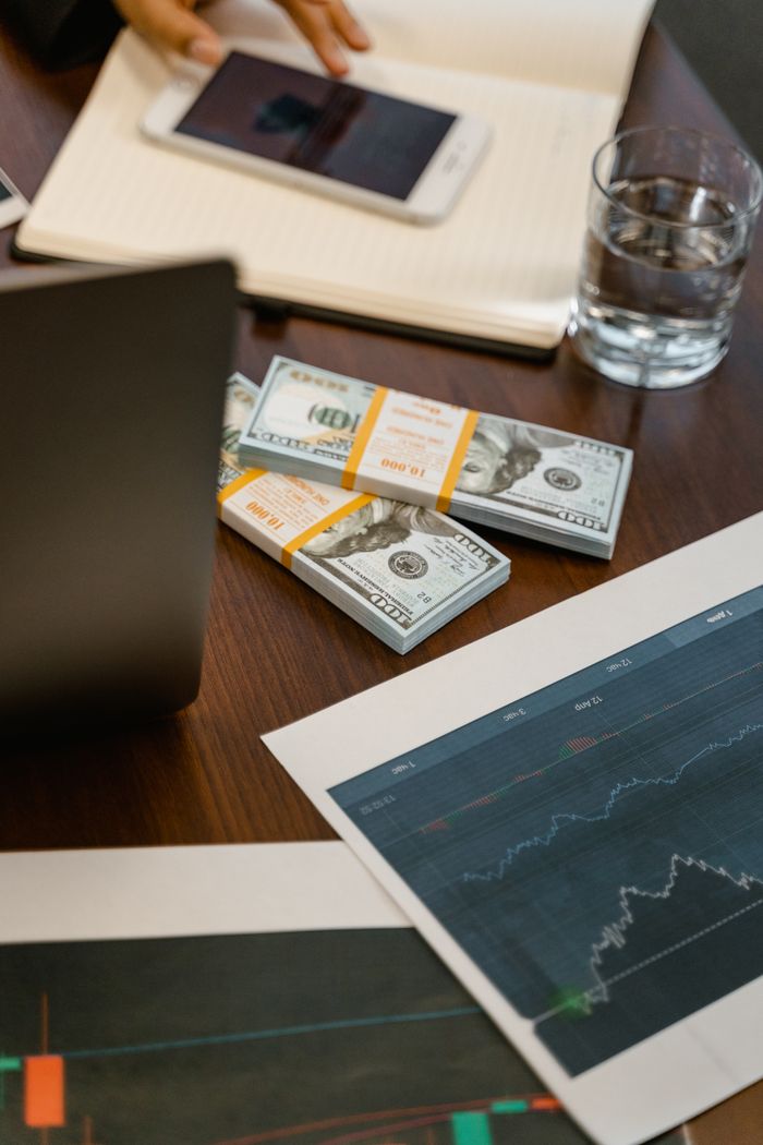 gallery-05 Stacks of US dollars and analytics charts on a wooden table, ideal for finance concepts.