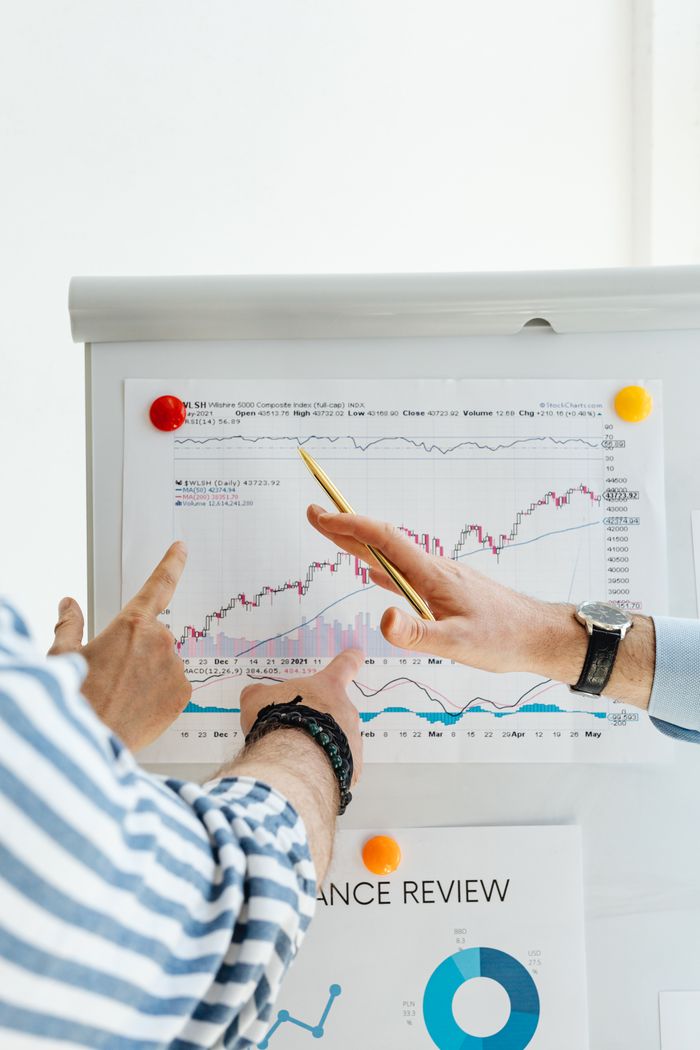 gallery-01 Two people analyzing financial charts on a whiteboard during a business meeting.